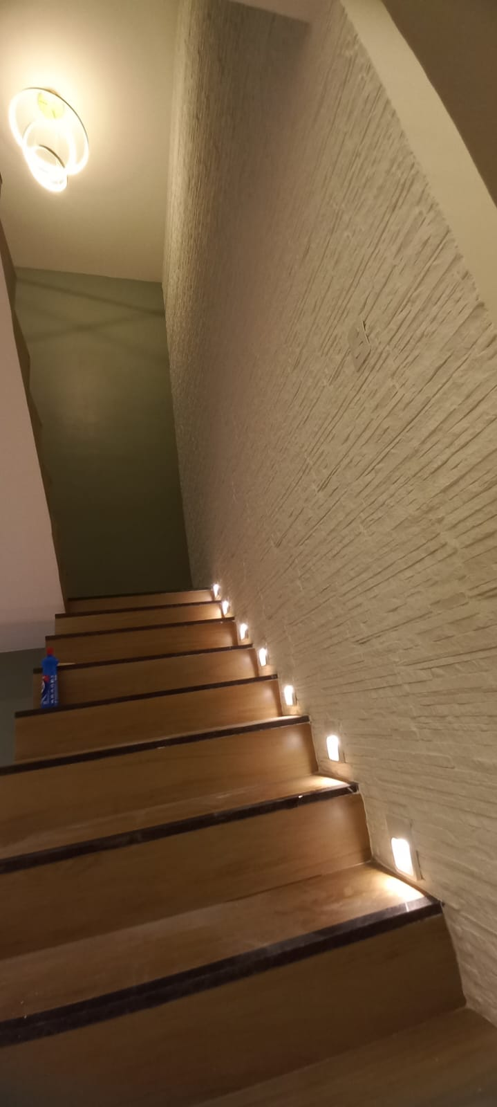 Escada com iluminação de balizadores e parede texturizada