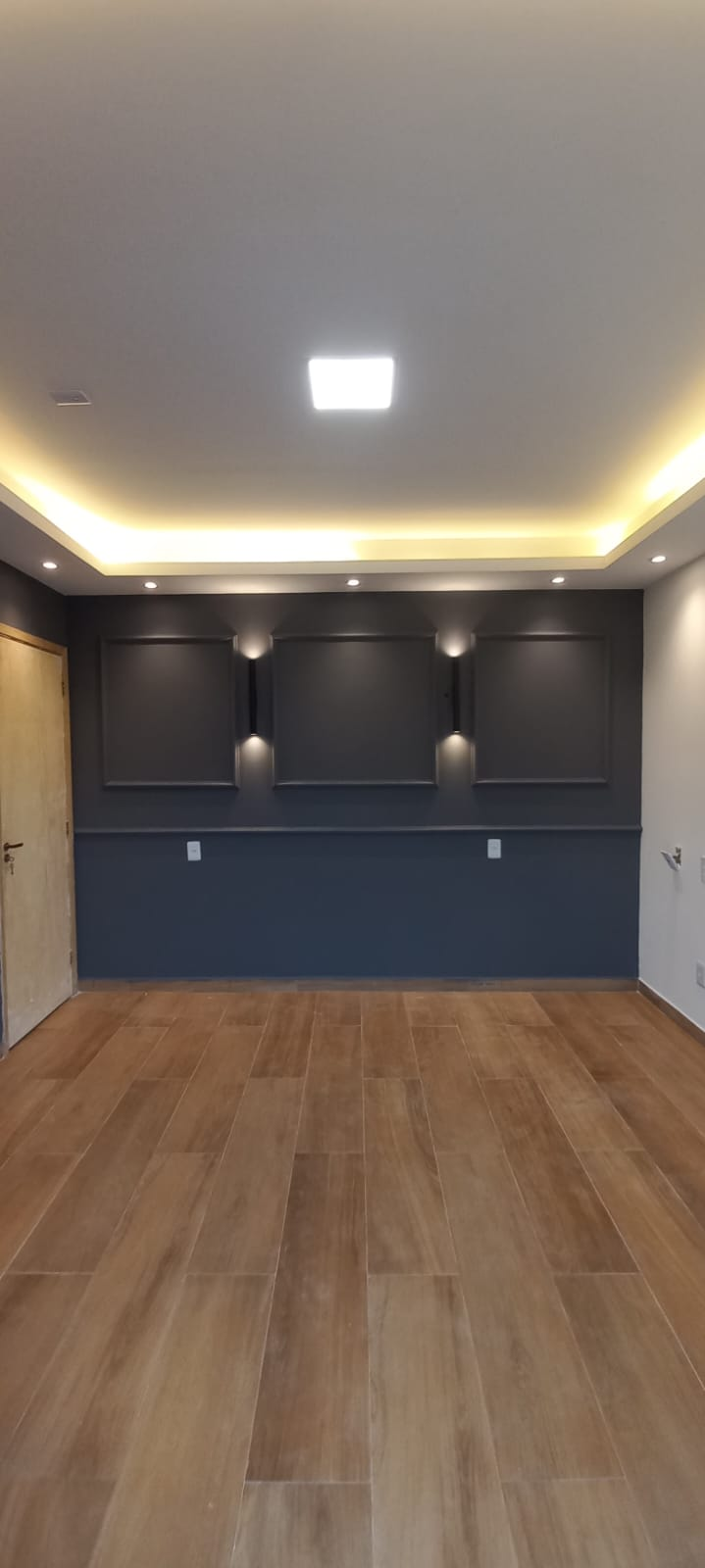 Sala com painel ripado, iluminação indireta e piso amadeirado
